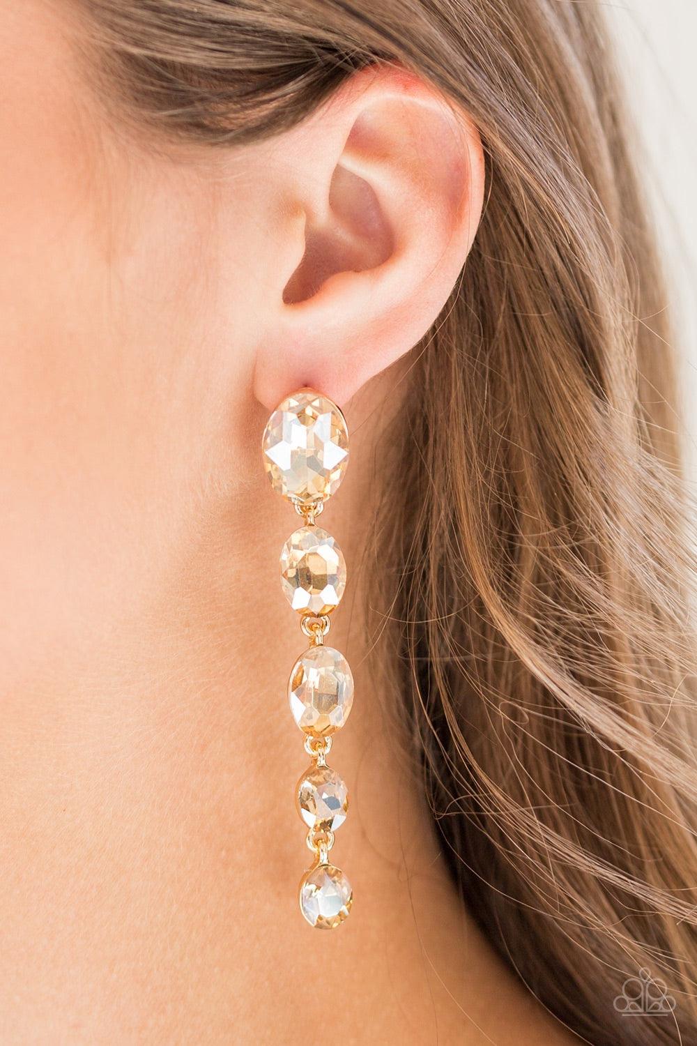 Paparazzi Accessories Red Carpet Radiance - Gold Gradually decreasing in size, golden gems trickle from the ear in a glamorous fashion. Earring attaches to a standard post fitting. Jewelry