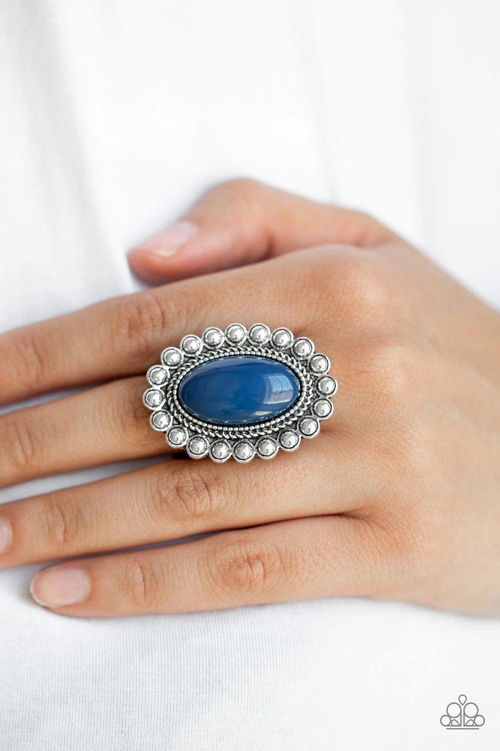 Paparazzi Accessories Ready to Pop ~Blue Painted in the confident shade of Evening Blue, an oversized blue bead is pressed into the center of a textured silver frame radiating in a ring of shimmery silver studs for a whimsical pop of color. Features a str