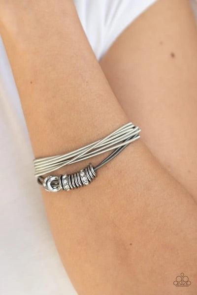 Paparazzi Accessories Magnetically Metro - Multi A collection of shiny gunmetal discs and white rhinestone encrusted rings slide along stretchy strands of spring-like gunmetal and silver bands for an edgy look. Features a magnetic closure. Sold as one ind