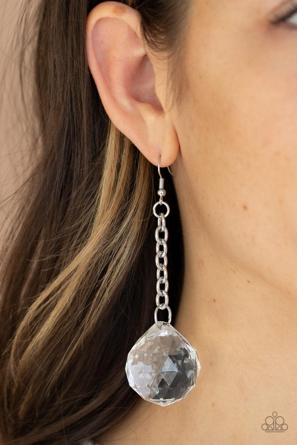 Paparazzi Accessories Spellbound Shimmer - White Featuring a faceted reflection, an exaggerated white gem-like bead dangles from the bottom of a shimmery silver chain for a prismatic look. Earring attaches to a standard fishhook fitting. Jewelry