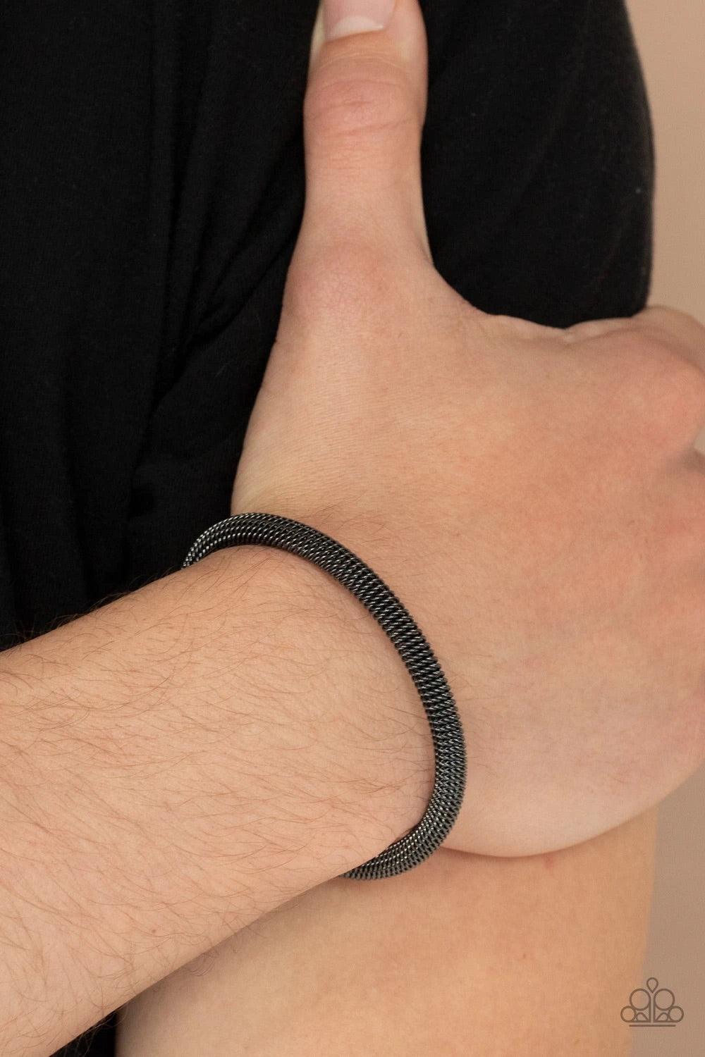 Paparazzi Accessories Metro Machiavellian - Black A dainty row of glistening gunmetal chain twists around a gunmetal cuff, creating an edgy industrial display around the wrist. Sold as one individual bracelet. Jewelry