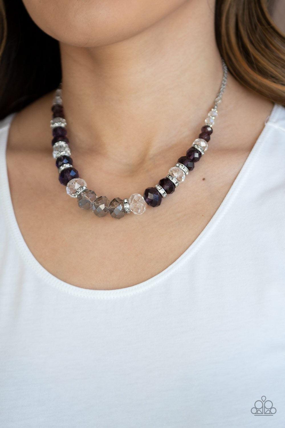 Paparazzi Accessories Distracted by Dazzle - Purple Attached to strands of shimmery silver chains, a glittery collection of purple, smoky, and white crystal-like gems and white rhinestone encrusted silver rings are threaded along an invisible wire below t