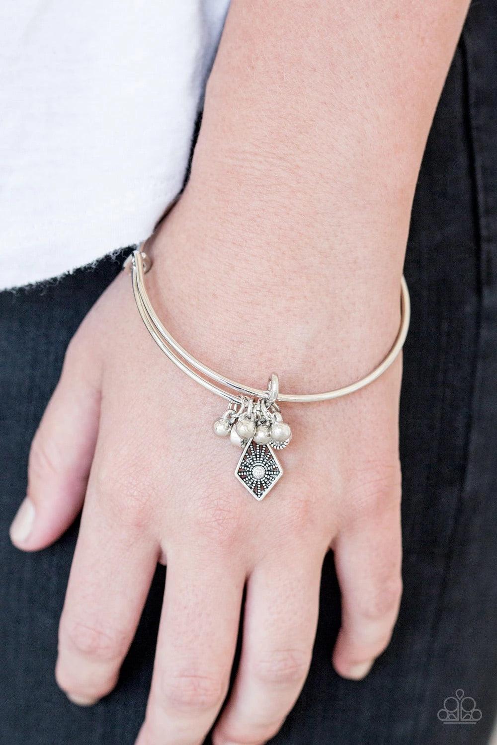 Paparazzi Accessories Treasure Charms - White A collection of shimmery silver beads and glittery white rhinestone accents slide along a sleek bar fitting, creating whimsical charms as they glide along the dainty silver bangle. Sold as one individual brace