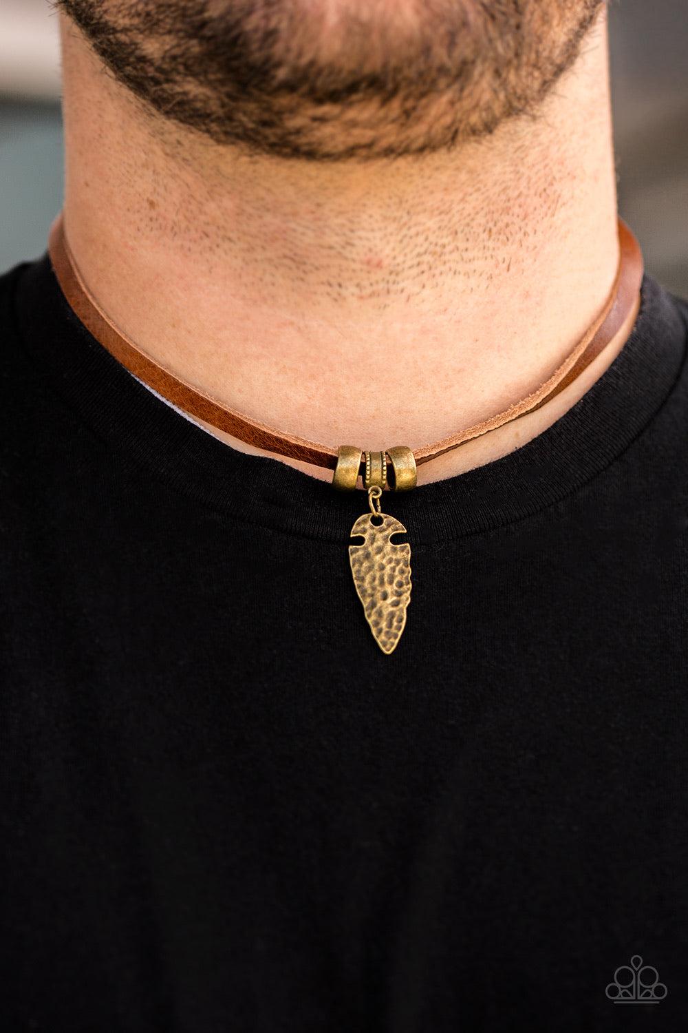 Paparazzi Accessories Every CAVEMAN For Himself - Brass Etched in tribal inspired textures, brass accents slide along a strand of brown leather for an urban look. Hammered in an antiqued shimmer, a brass arrowhead pendant swings from the center for an ind