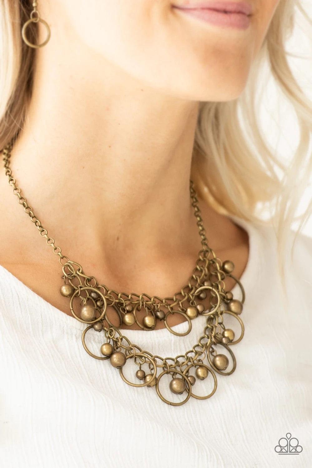 Paparazzi Accessories Warning Bells - Brass Brushed in an antiqued finish, mismatched brass beads and airy brass hoops swing from two rows of brass chains, creating an edgy fringe below the collar. Features an adjustable clasp closure. Sold as one individ