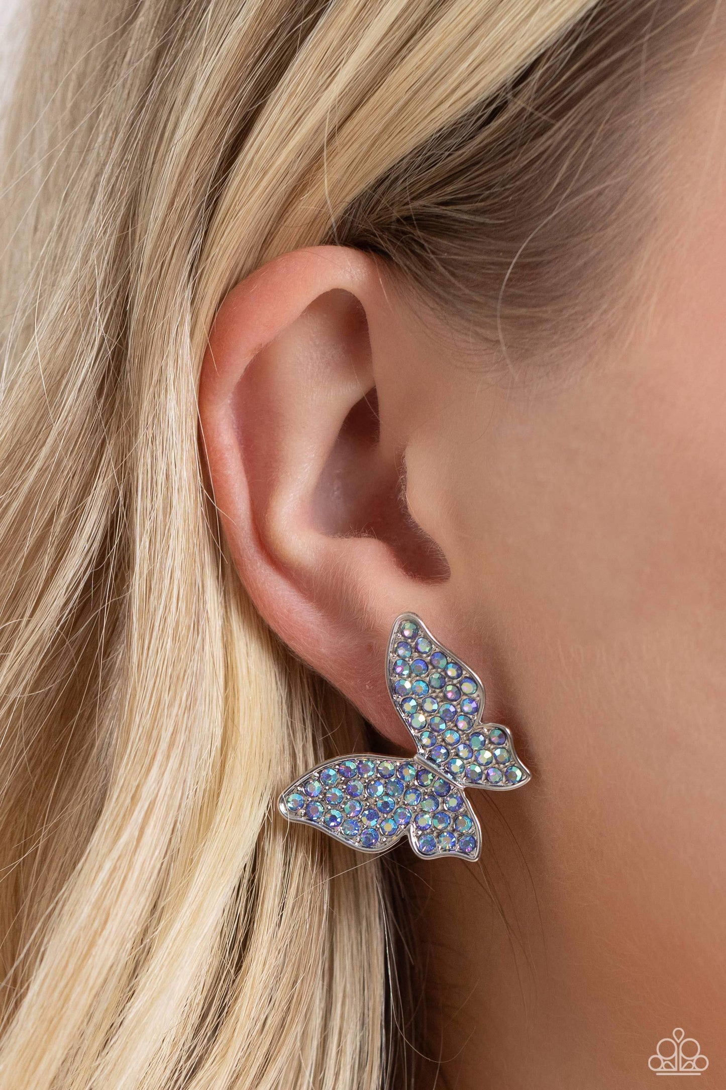 Paparazzi Accessories High Life - Blue Featuring a tilted motif, a silver butterfly encrusted with an explosion of blue iridescent rhinestones sparkles at the ear for an enchanting fashion. Earring attaches to a standard post fitting. Due to its prismatic