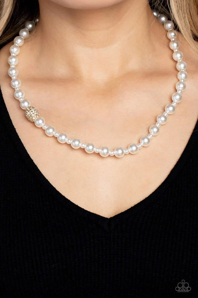 Paparazzi Accessories Countess Chic - Gold Strung along the entirety of an invisible wire, classic white pearls in varying sizes coalesce down the neckline for a refined finish. Adding to the elegant design, a sparkly white rhinestone-encrusted gold ornam