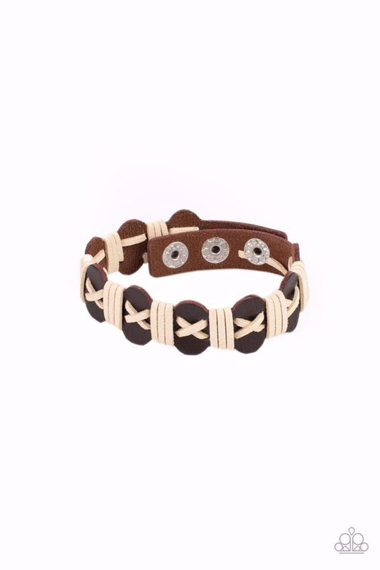 Paparazzi Accessories Macho Maverick - Brown White suede cording is threaded in a crisscross pattern along the front of a wavy brown suede band. Additional white cording wraps across the scalloped band in intervals creating a rustic handmade look. Feature