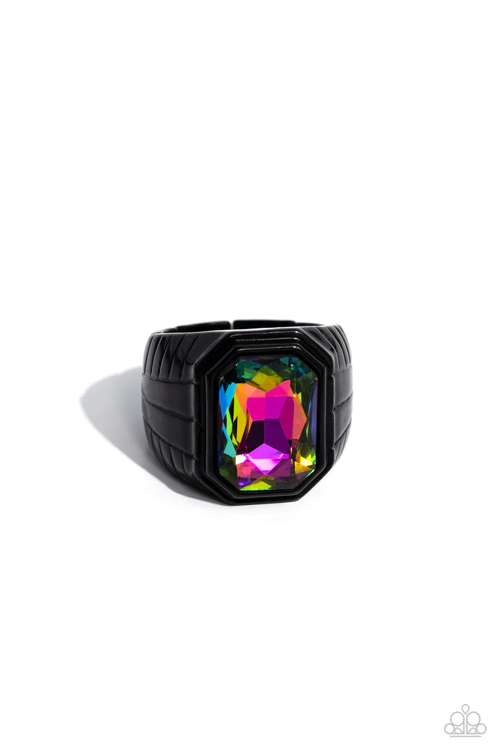 Paparazzi Accessories Cavalier Claim - Multi Featuring a regal emerald style cut, a glittery oil spill gem is pressed into a sleek black frame featuring a thick black band embossed in bold textures. Features a stretchy band for a flexible fit. Sold as one