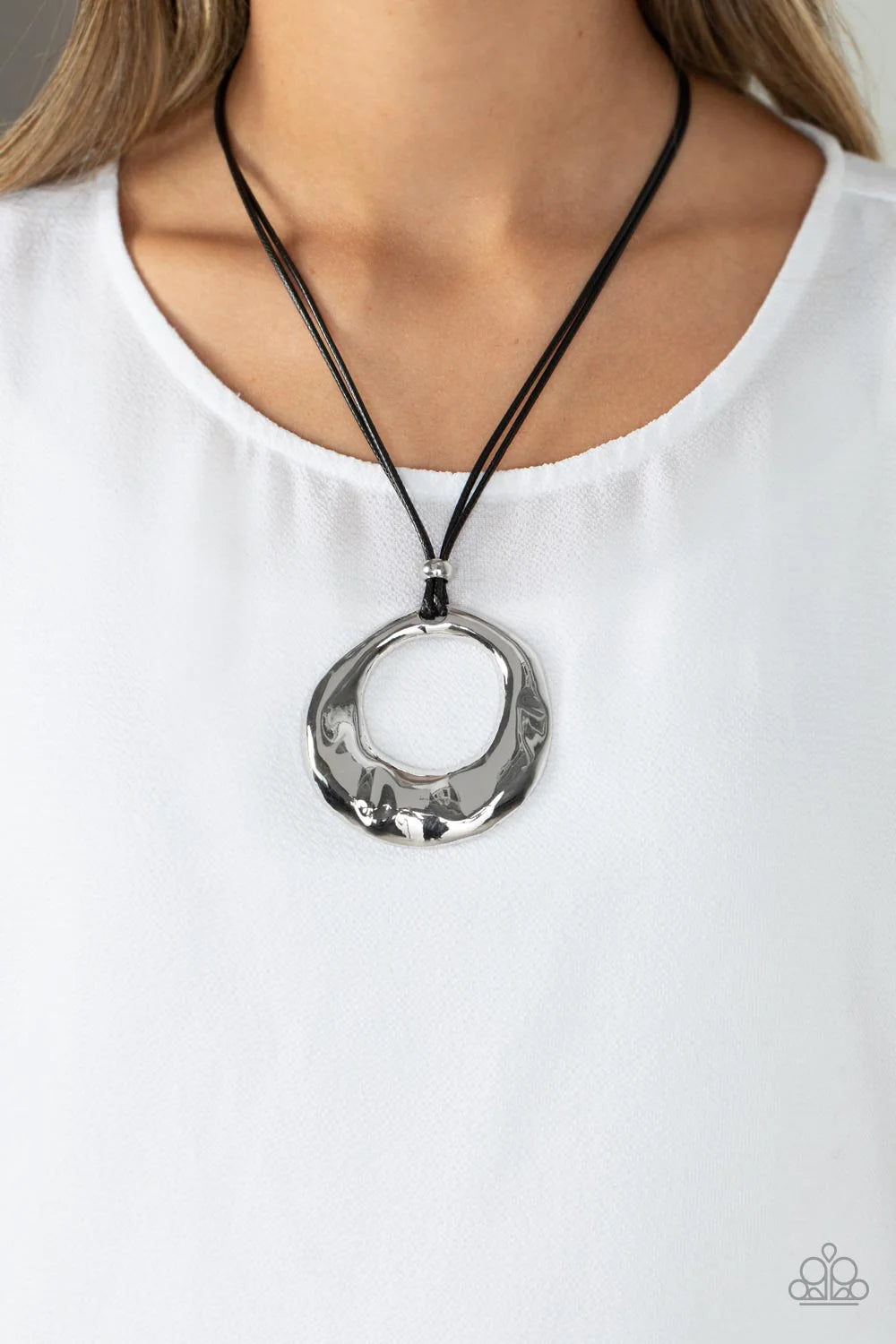 Paparazzi Accessories Tectonic Treasure - Silver An oversized, oblong, silver hoop rippling with hammered textures swings from the bottom of a collection of black cording. A single silver bead glides down the bottom of the cording for a dramatic industria