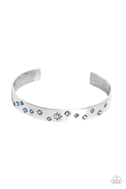 Paparazzi Accessories Starburst Shimmer - Blue Tinted in subtle, stellar shades of blue and iridescence, dainty rhinestones are pressed into the centers of stamped stars in varying sizes. Embossed in tactile textures, the starry collection wraps around th