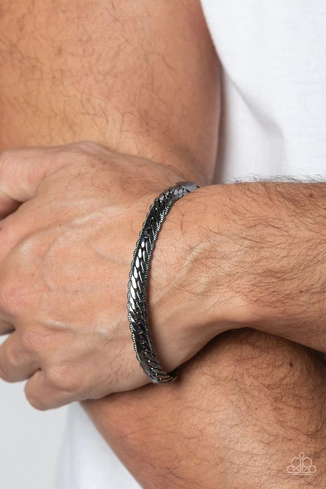 Paparazzi Accessories Cargo Couture - Black Brushed in a high-sheen finish, a thick, gunmetal chain wraps around the wrist for an industrial look. Featured within the design, the chain seems to tightly stack on top of itself, emitting light from every ang