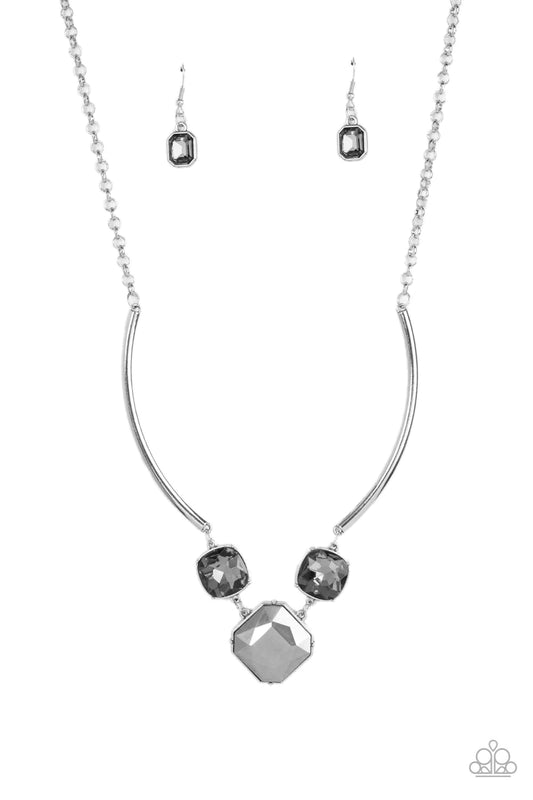 Paparazzi Accessories Divine IRIDESCENCE - Silver An oversized collection of radiant cut smoky and hematite gems delicately link at the bottom of two curved silver rods. Attached to shiny silver chains, the glamorously glitzy display sparkles below the co
