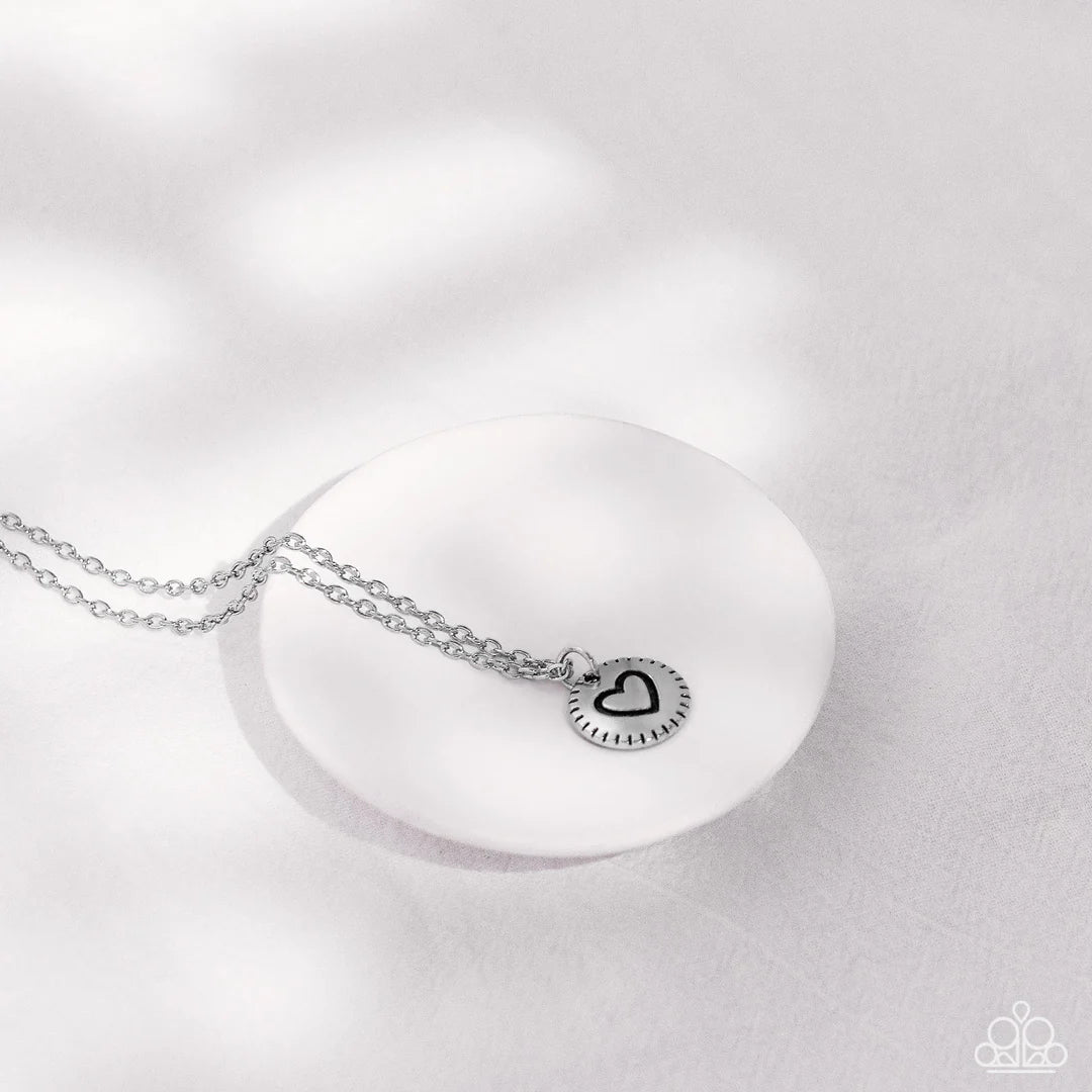 Paparazzi Accessories Stamped Sentiment - Silver Stamped in a heart burst pattern, a round silver pendant is suspended from a dainty silver chain for a sentimentally sleek design. Features an adjustable clasp closure. Sold as one individual necklace. Incl