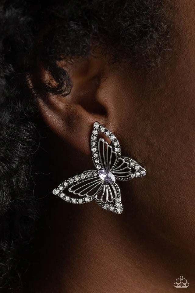 Paparazzi Accessories Wispy Wings - Purple The outer wings of a white gem-studded butterfly feature inner lacy, airy silver wings that bloom from a marquise-cut purple gem center, coalescing into a whimsical 3D butterfly design. Earring attaches to a stan