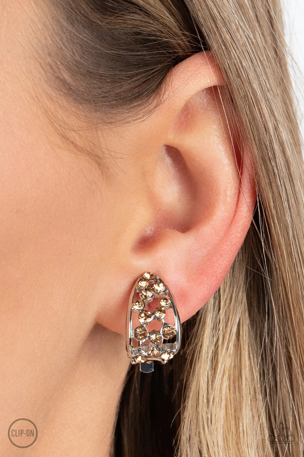 Paparazzi Accessories Extra Effervescent - Brown A collection of dainty golden topaz rhinestones tumbles down the airy center of a curved silver frame, resulting in a stellar effervescence. Earring attaches to a standard clip-on fitting. Sold as one pair