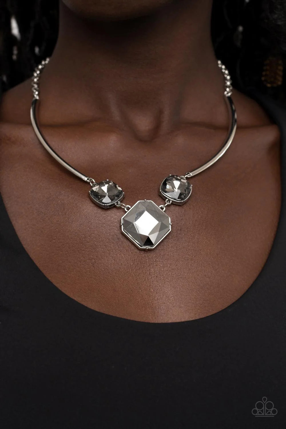 Paparazzi Accessories Divine IRIDESCENCE - Silver An oversized collection of radiant cut smoky and hematite gems delicately link at the bottom of two curved silver rods. Attached to shiny silver chains, the glamorously glitzy display sparkles below the co