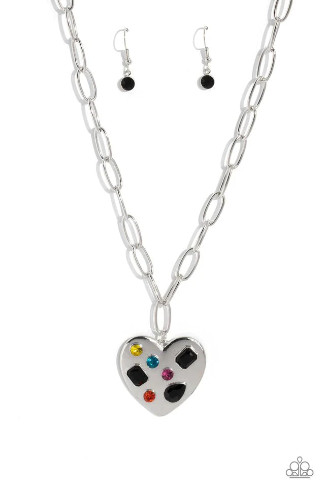 Paparazzi Accessories Online Dating - Black Falling down the neckline from a shimmery silver paperclip chain, an oversized silver heart rests for a romantic statement. Brushed with shimmery pink, yellow, orange, blue, and black gems in round, teardrop and