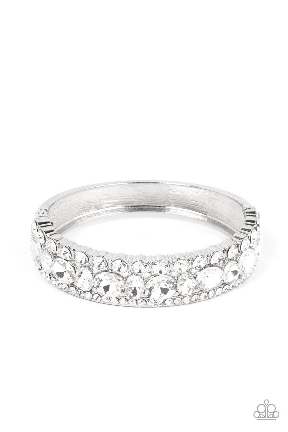 Paparazzi Accessories Mega Megawatt - White Three blinding rows of mismatched white rhinestones dramatically stack across the wrist, coalescing into a majestic bangle-like centerpiece. Features a hinged closure. Sold as one individual bracelet. Bracelets