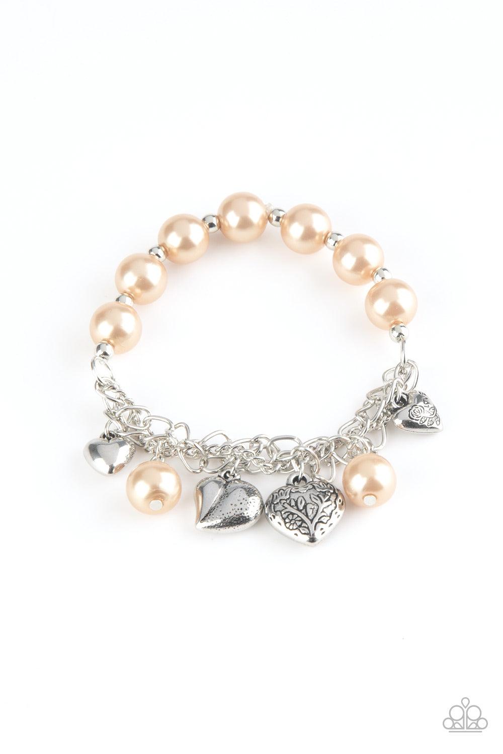 Paparazzi Accessories More Amour - Brown Attached to a section of shimmery silver chain, pearly brown and dainty silver beads are threaded along a stretchy band. Mismatched silver heart charms swing from the glistening chain, creating a flirty fringe. Sol