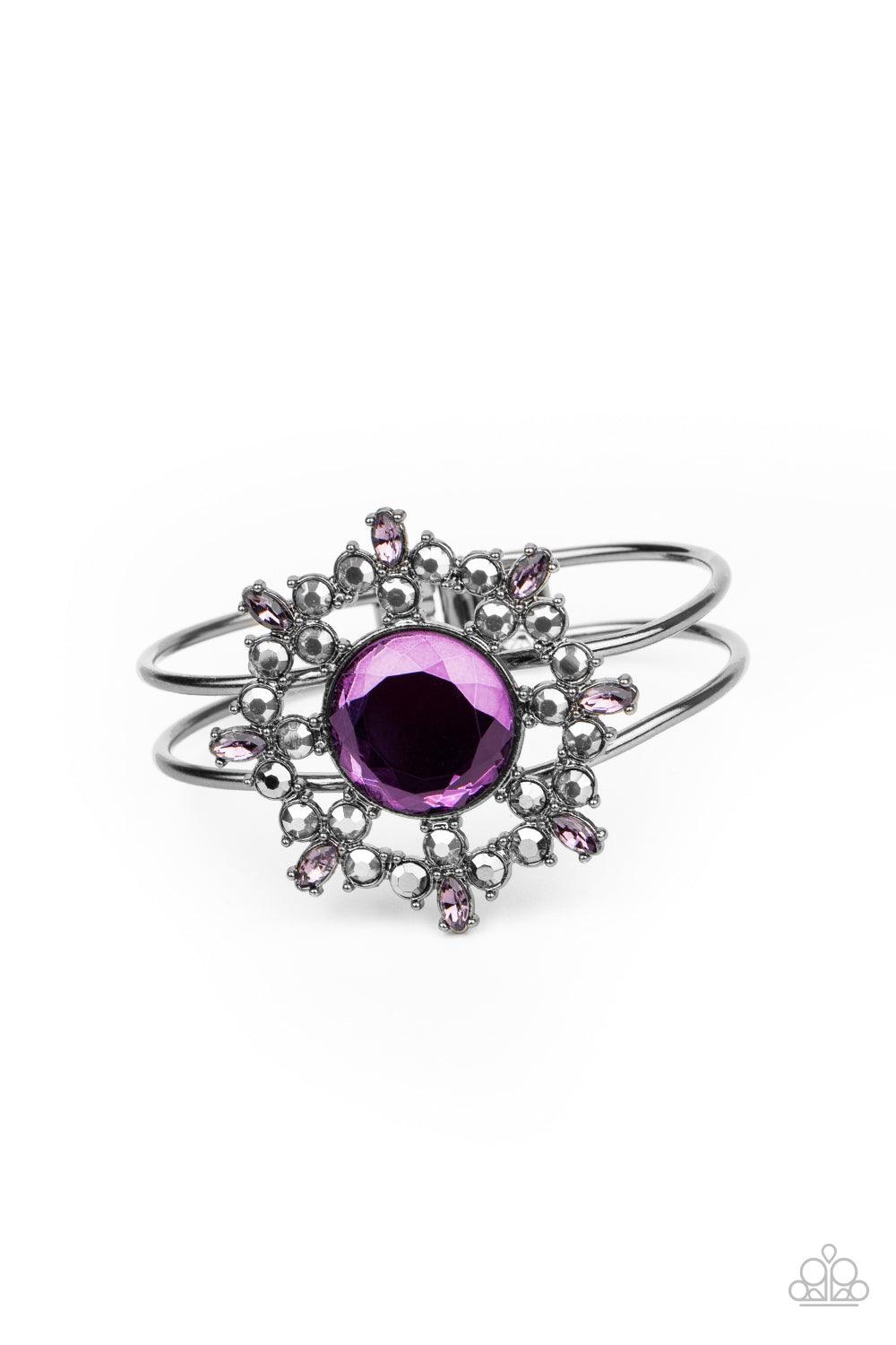 Paparazzi Accessories Elaborate Elegance - Purple Glittery purple and hematite petals bloom from an oversized purple rhinestone center, creating a dazzling floral centerpiece atop an airy gunmetal cuff. Features a hinged closure. Sold as one individual br