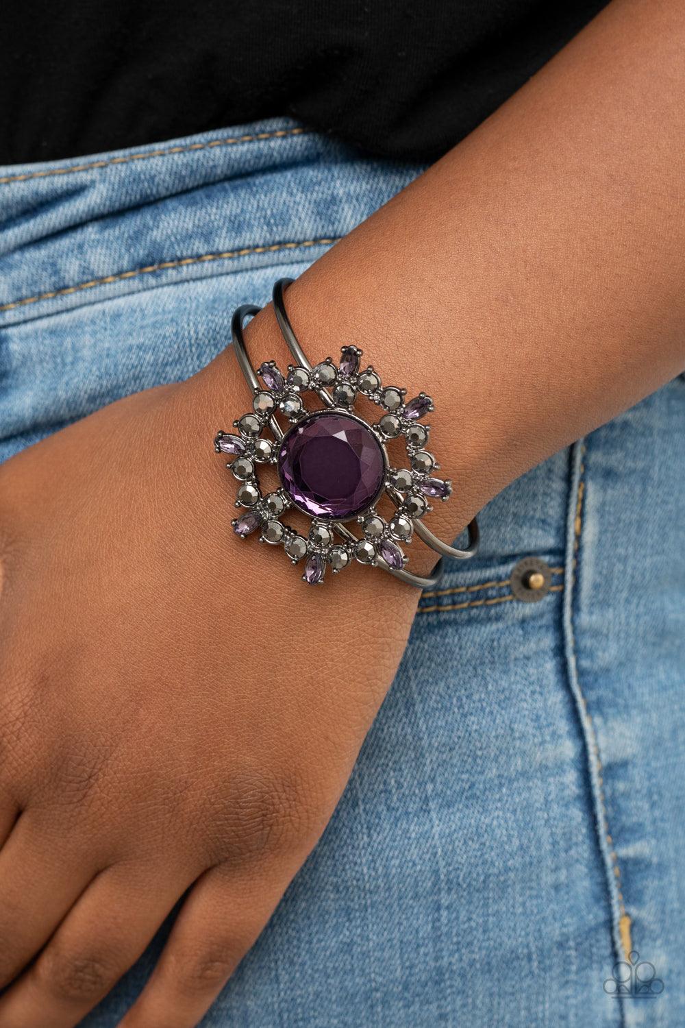 Paparazzi Accessories Elaborate Elegance - Purple Glittery purple and hematite petals bloom from an oversized purple rhinestone center, creating a dazzling floral centerpiece atop an airy gunmetal cuff. Features a hinged closure. Sold as one individual br