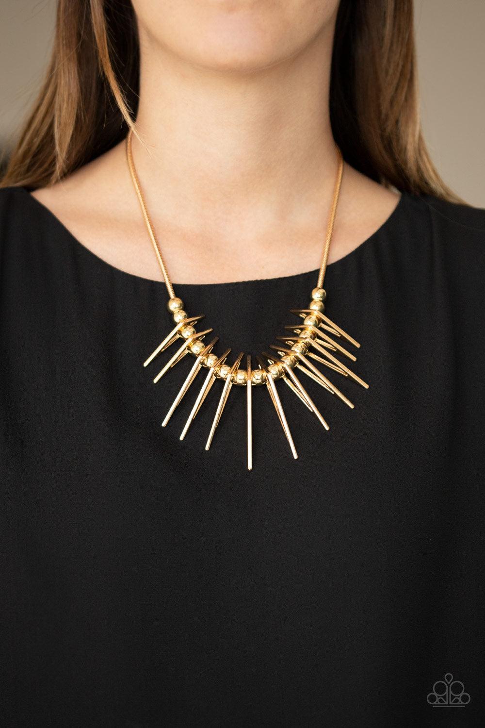 Paparazzi Accessories Fully Charged - Gold Separated by bold gold beads, triangular gold frames gradually increase in intensity as they slide along a rounded gold snake chain, creating an edgy fringe below the collar. Features an adjustable clasp closure.