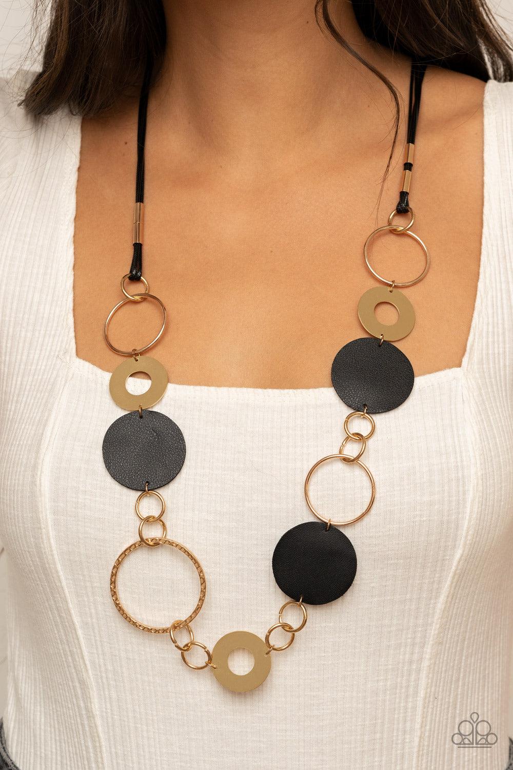Paparazzi Accessories Sooner or LEATHER - Black A shiny collection of mismatched gold rings and textured hoops link with round pieces of black leather across the chest for a whimsically retro look. The colorful compilation attaches to layered strands of s