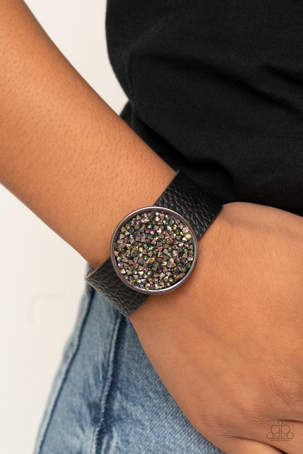 Paparazzi Accessories Stellar Escape - Multi A smoldering display of hematite and oil spill rhinestones scatter across the front of a gunmetal disc that glides along a black leather band for a stellar look. Features an adjustable snap closure. Sold as one
