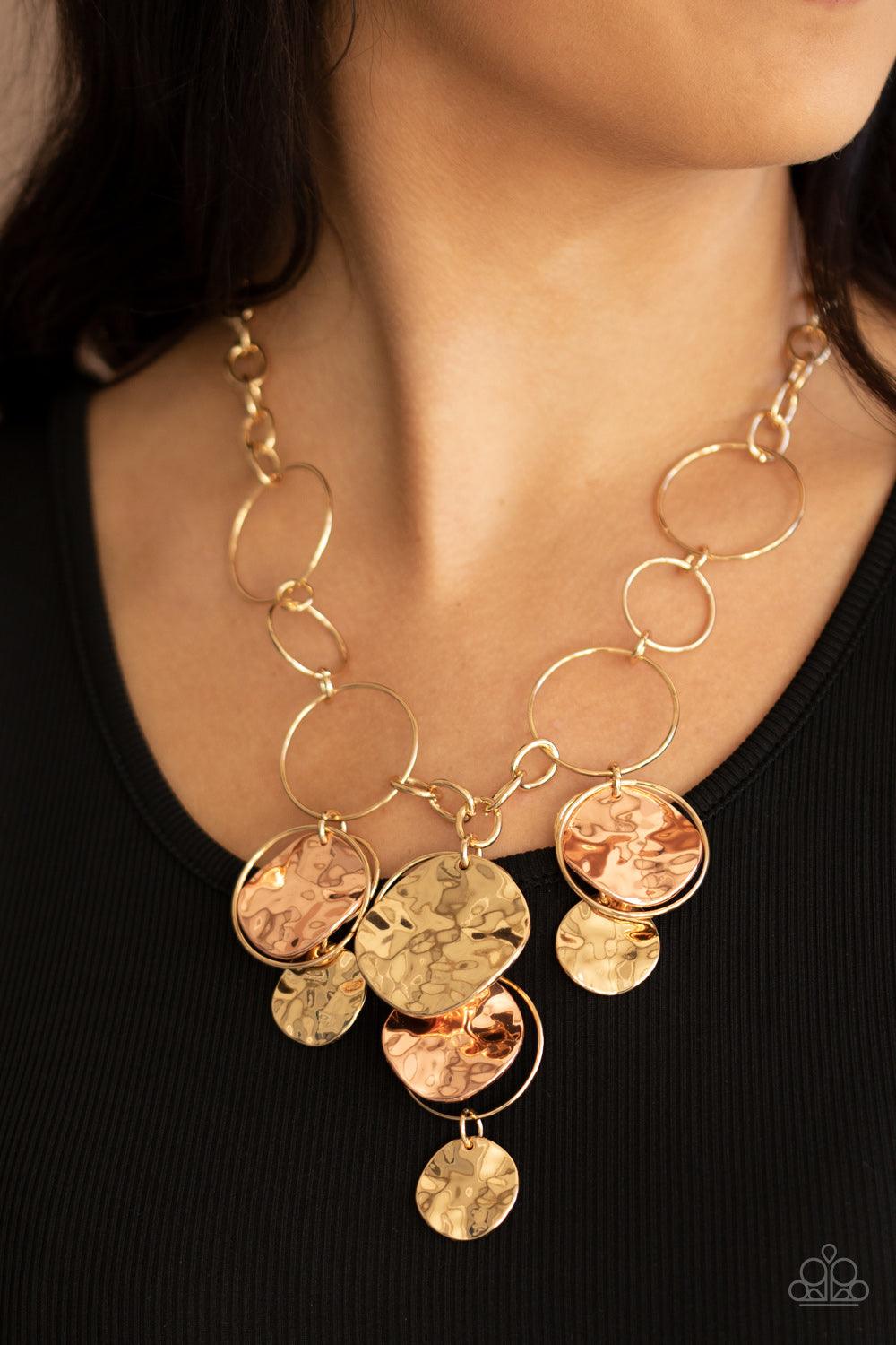 Paparazzi Accessories Learn The HARDWARE Way - Gold Glistening gold hoops link with a section of chunky gold chain below the collar. A shimmery collection of gold hoops and hammered gold and shiny copper discs cascade from the bottom of the golden display