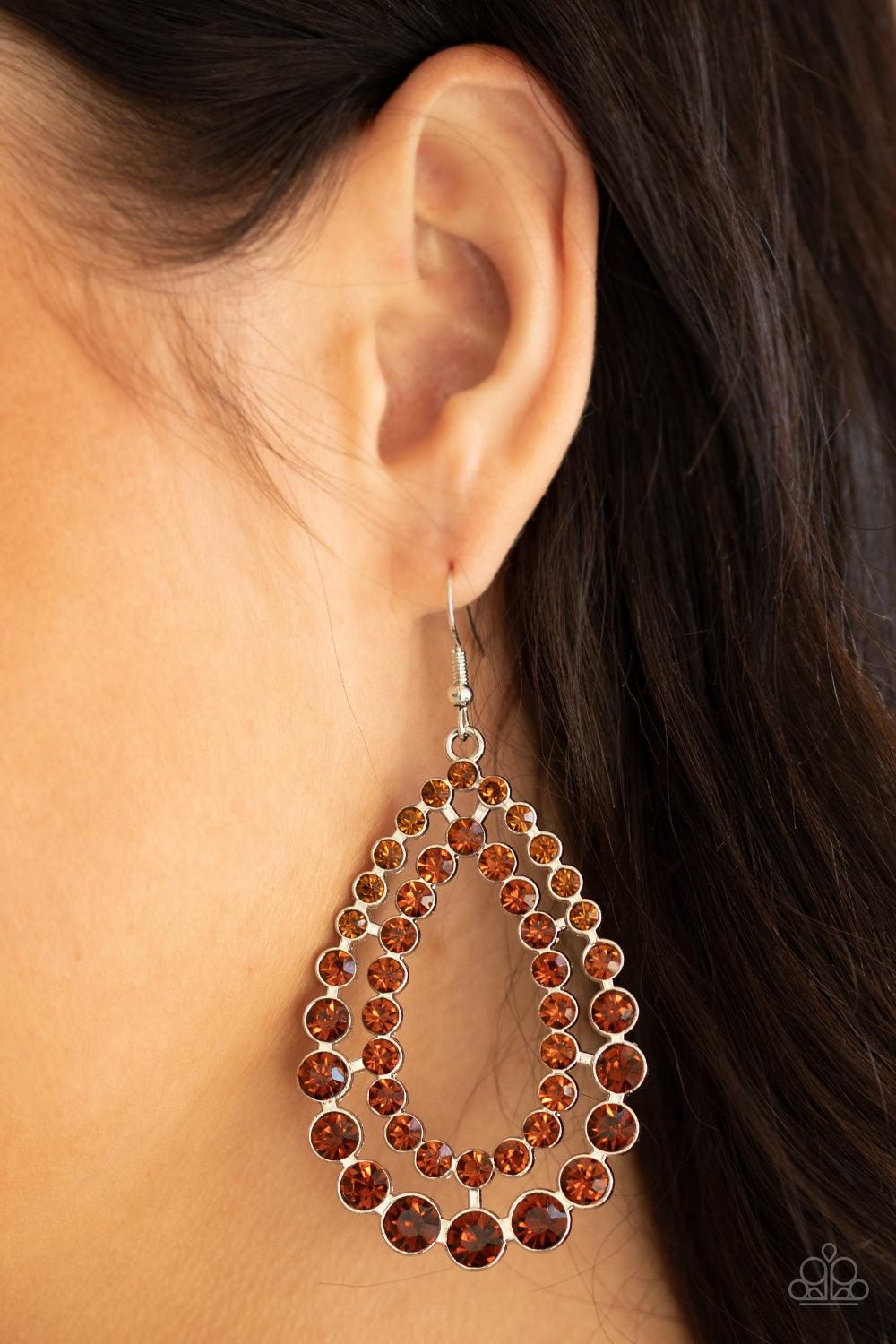 Paparazzi Accessories Glacial Glaze - Brown Varying in size, rows of glittery topaz rhinestones coalesce into two blinding teardrops for a jaw-dropping dazzle. Earring attaches to a standard fishhook fitting. Sold as one pair of earrings. Jewelry