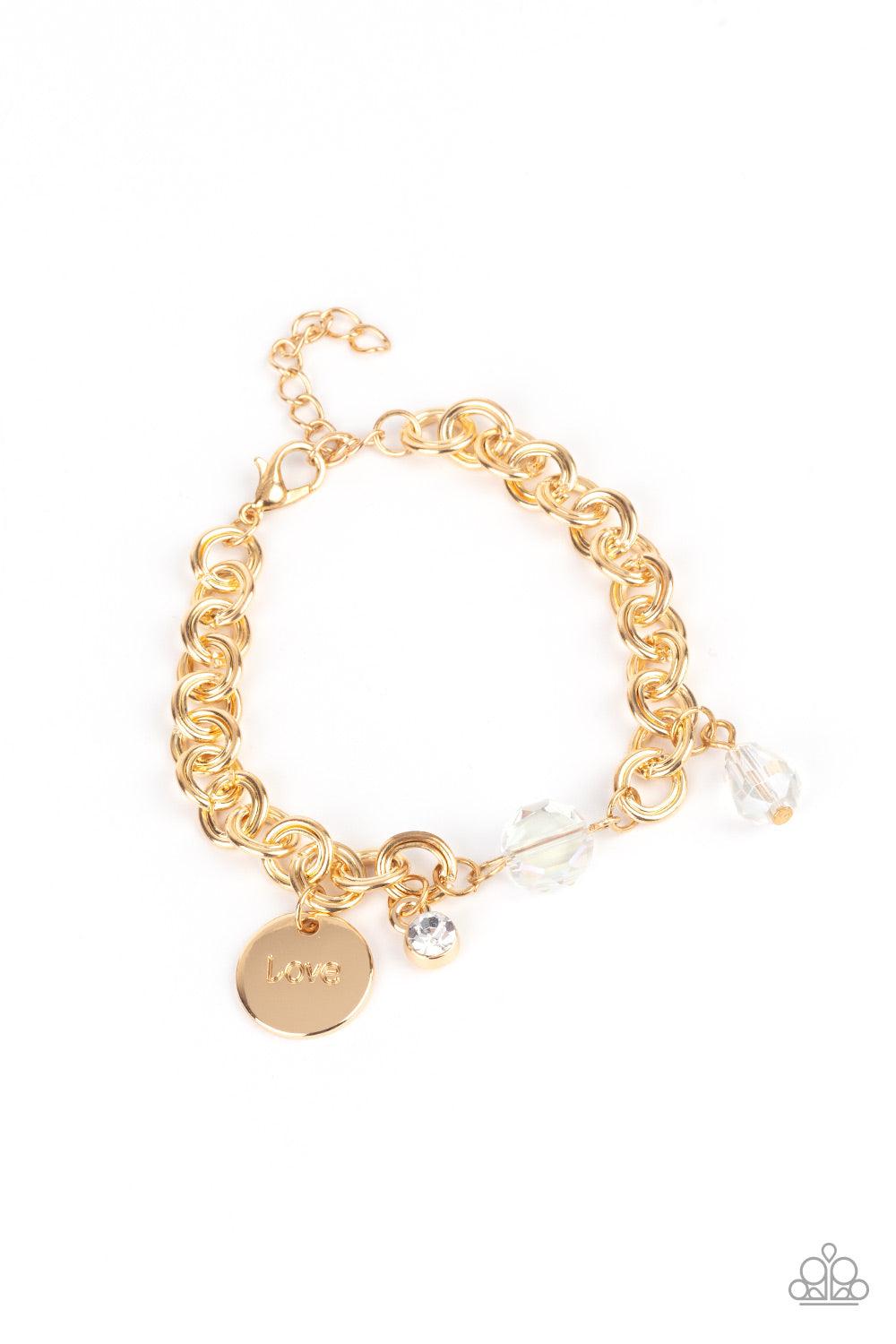 Paparazzi Accessories Lovable Luster - Gold White crystal-like beads, a dainty white rhinestone, and a gold disc stamped in the word, "love," adorn a double-linked gold chain, creating a flirty fringe around the wrist. Features an adjustable clasp closure