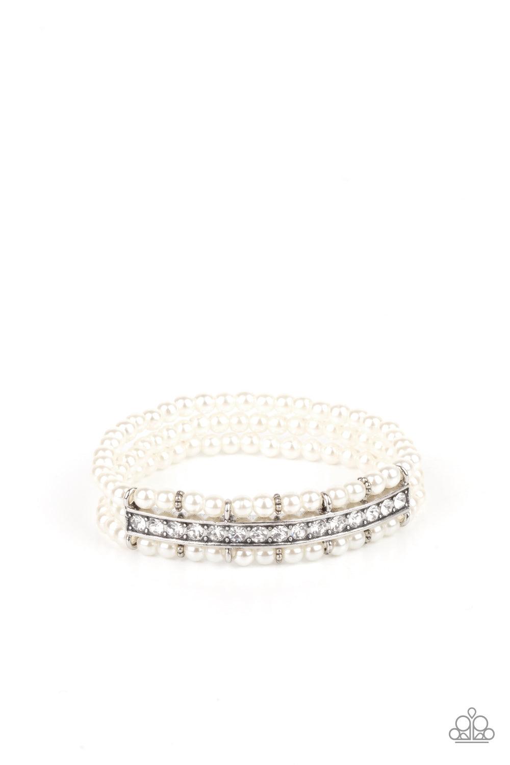 Paparazzi Accessories Vintage Beam - White Threaded along stretchy bands, three rows of dainty white pearls are held in place around the wrist by a white rhinestone encrusted centerpiece for a romantic flair. Sold as one individual bracelet. Bracelets