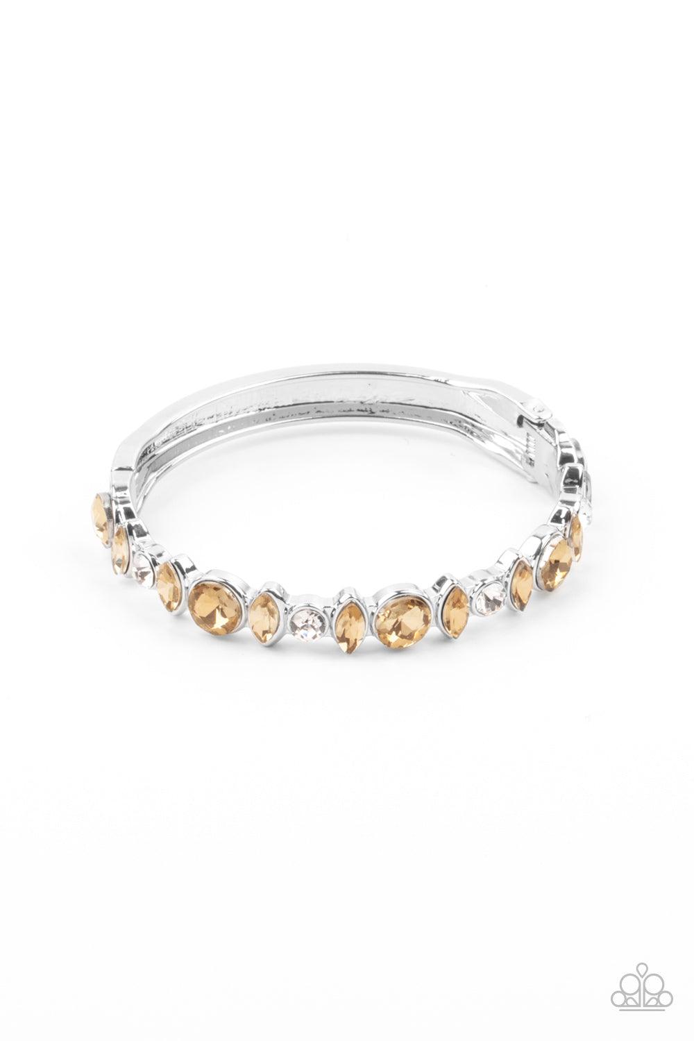 Paparazzi Accessories BLING Them To Their Knees - Brown A blinding collection of round and marquise-cut golden topaz and white rhinestones are encrusted across the front of a shiny silver bar, curling around the wrist to create a timeless cuff-like bangle