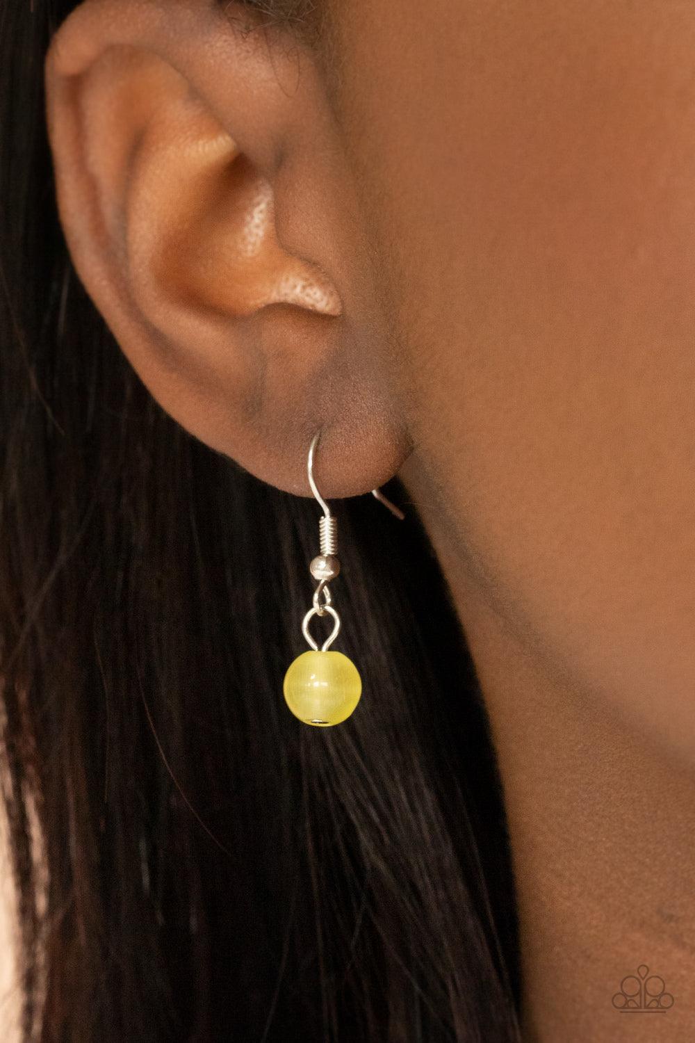 Paparazzi Accessories Warmhearted Glow - Yellow An oversized Illuminating cat's eye stone frame swings from the bottom of a lengthened silver chain, creating a flirtatious pendant. Features an adjustable clasp closure. Sold as one individual necklace. Inc