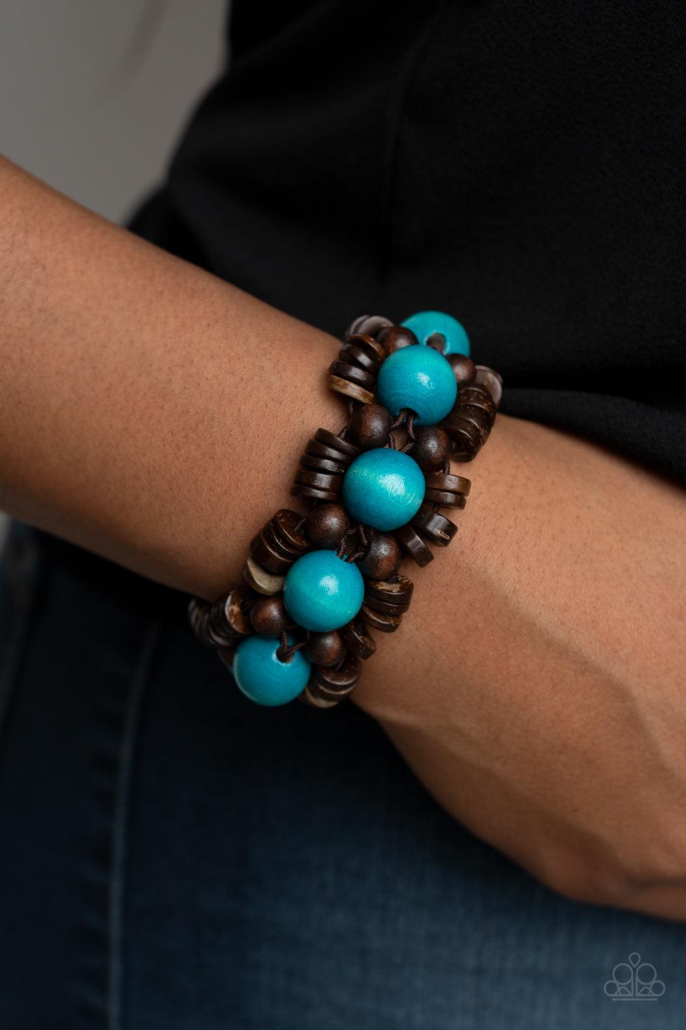 Paparazzi Accessories Tropical Temptations - Blue Oversized blue wooden beads, rustic brown wooden beads, and dainty wooden discs are ornately threaded along braided stretchy bands around the wrist, creating a summery centerpiece. Sold as one individual b