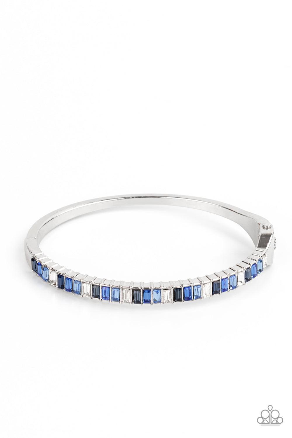 Paparazzi Accessories Toast to Twinkle - Blue Featuring regal emerald style cuts, a dainty row of blue and white rhinestones are encrusted across the front of a silver cuff-like bangle for a timeless fashion. Features a hinged closure. Sold as one individ