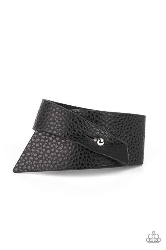 Paparazzi Accessories PIECE Offering - Black A triangular piece of black leather delicately wraps around the wrist, creating an edgy asymmetrical centerpiece around the wrist. Features a studded button loop closure. Sold as one individual bracelet. Bracel
