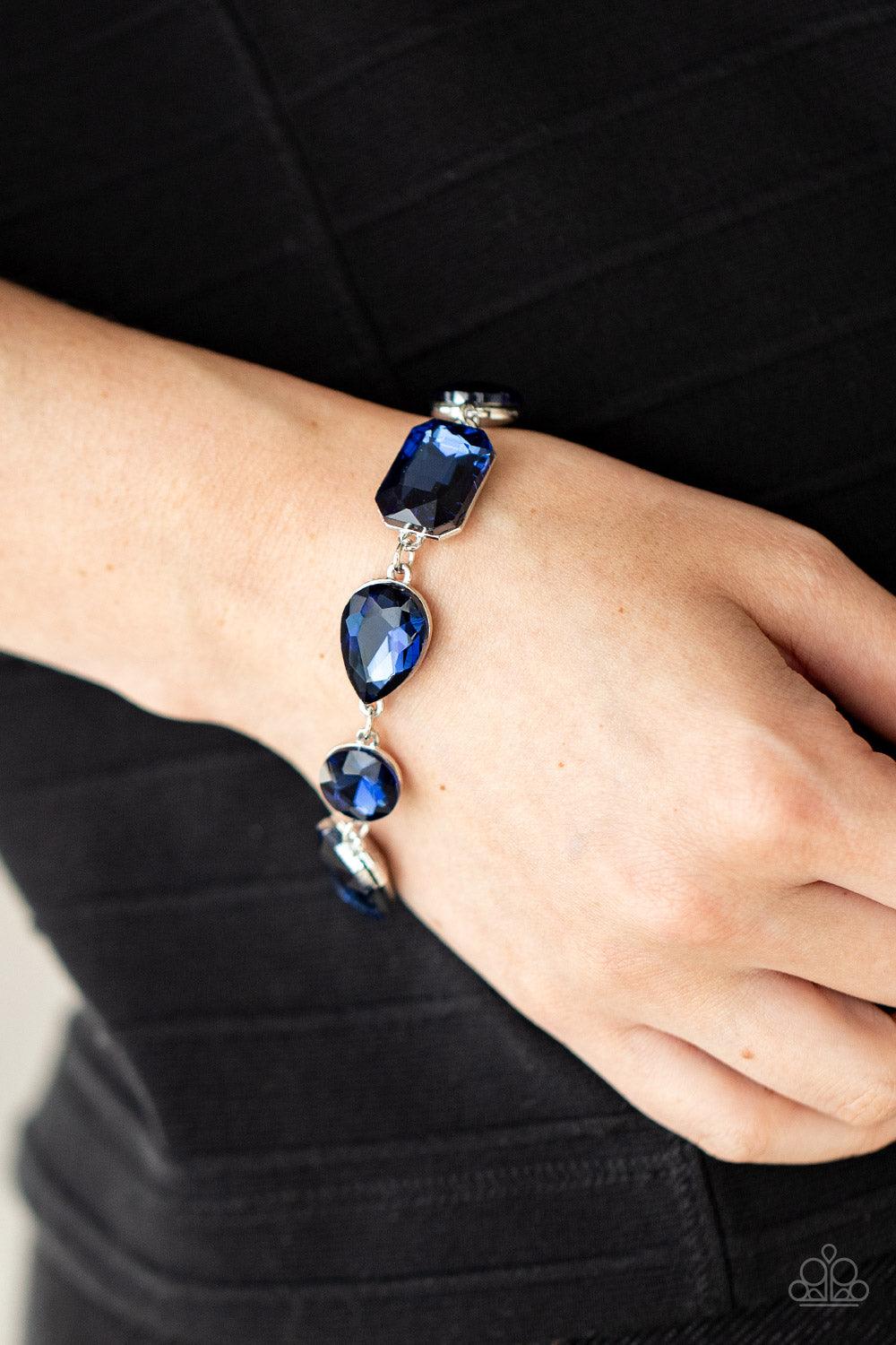 Paparazzi Accessories Cosmic Treasure Chest - Blue A collection of oversized round, teardrop, and emerald cut blue rhinestones delicately link around the wrist, creating a blinding statement piece. Features an adjustable clasp closure. Sold as one individ