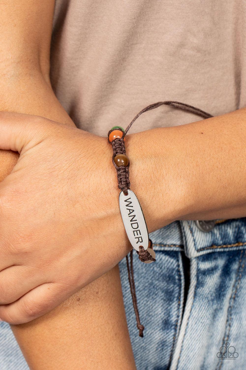 Paparazzi Accessories Roaming For Days - Multi Glassy multicolored cat's eye stone beads are knotted in place along a strand of braided brown cording that attaches to a silver centerpiece stamped in the word, "Wander," for a free-spirited fashion. Feature