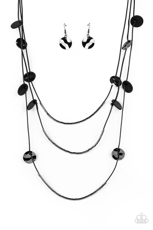 Paparazzi Accessories Alluring Luxe - Black Shining wavy gunmetal discs and black leather discs adorn a trio of lengthened subtly shimmering black cords. Rows of dainty gunmetal cylinders are threaded along the bottom of each cord adding luxurious allure