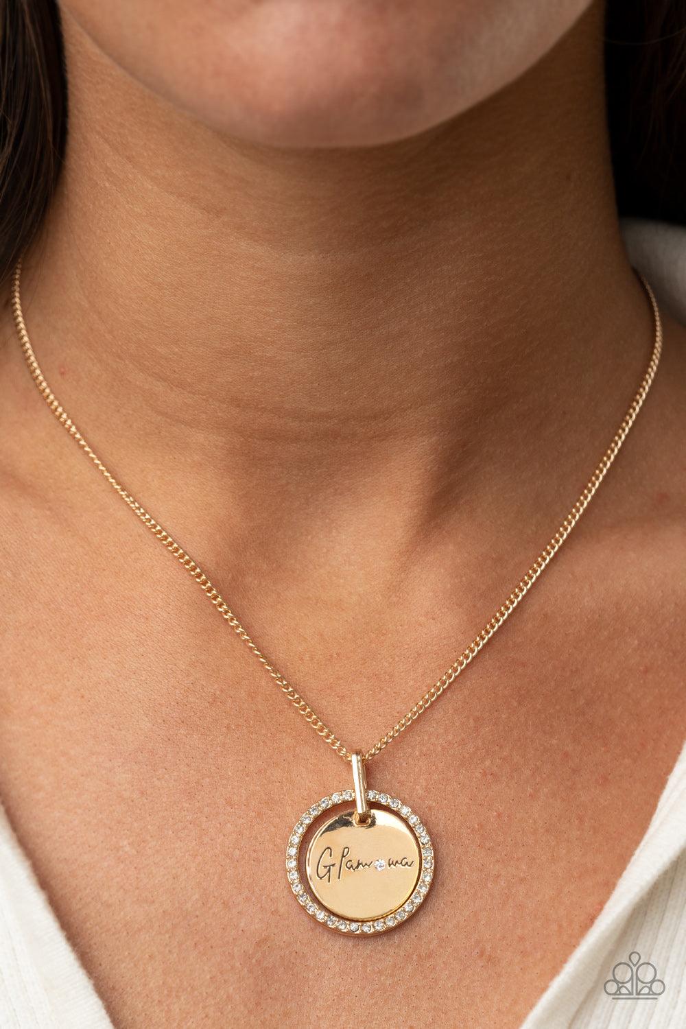 Paparazzi Accessories Glam-ma Glamorous - Gold Infused with a gold ring of glassy white rhinestones, a glistening gold disc is dotted with a dainty white rhinestone and stamped in the word, "Glamma," as it swings below the collar for a glamorously sentime
