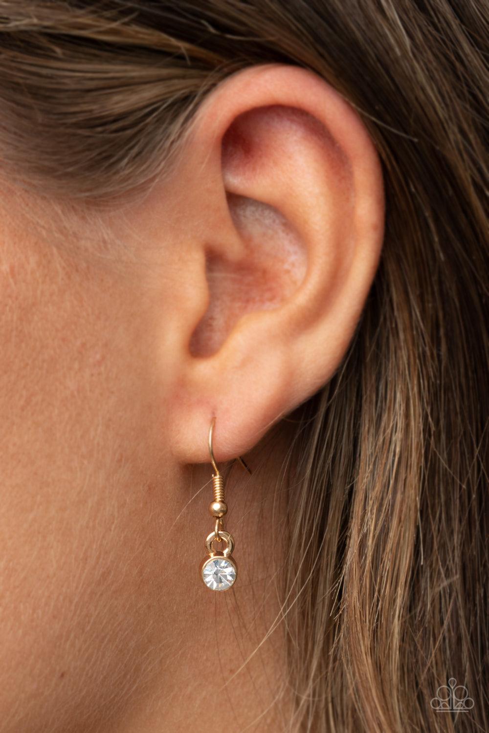 Paparazzi Accessories Glam-ma Glamorous - Gold Infused with a gold ring of glassy white rhinestones, a glistening gold disc is dotted with a dainty white rhinestone and stamped in the word, "Glamma," as it swings below the collar for a glamorously sentime
