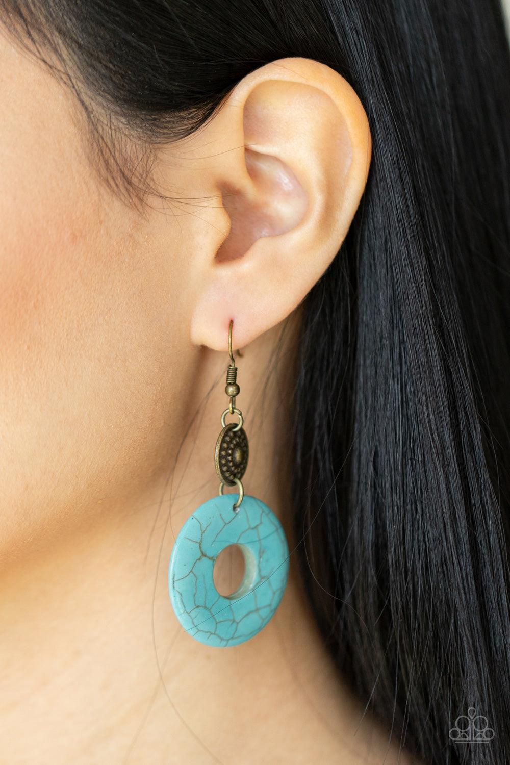 Paparazzi Accessories Earthy Epicenter - Brass A large turquoise ring dangles from an antiqued brass disc, accented with raised dots in concentric circles. The timeless combination of turquoise and brass and the intricate textures bring an undeniably arti
