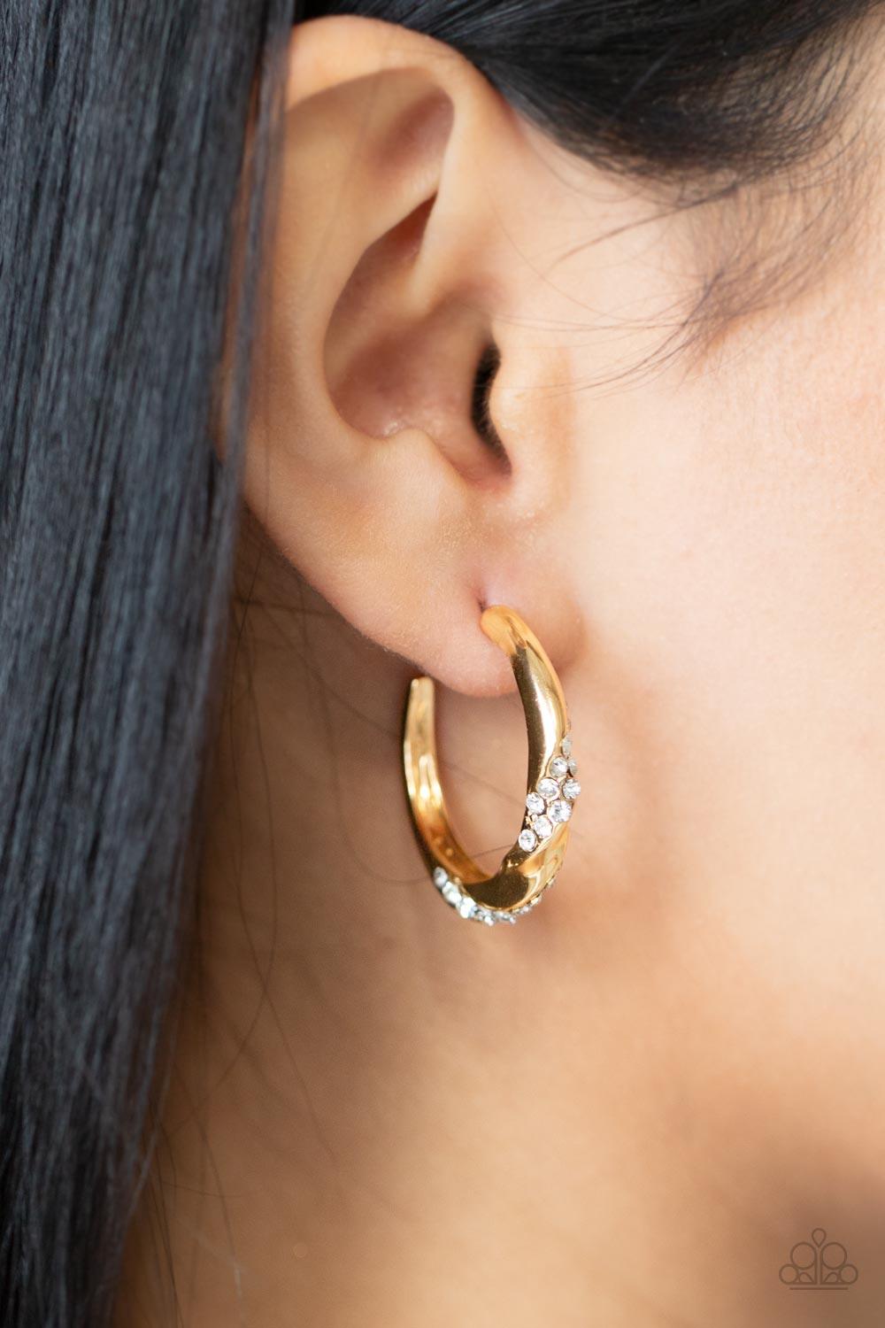 Paparazzi Accessories Subliminal Shimmer - Gold Ribbons of white rhinestones wrap around a dainty gold hoop that has been chiseled and twisted, adding extra dimension. Earring attaches to a standard post fitting. Hoop measures approximately 1" in diameter