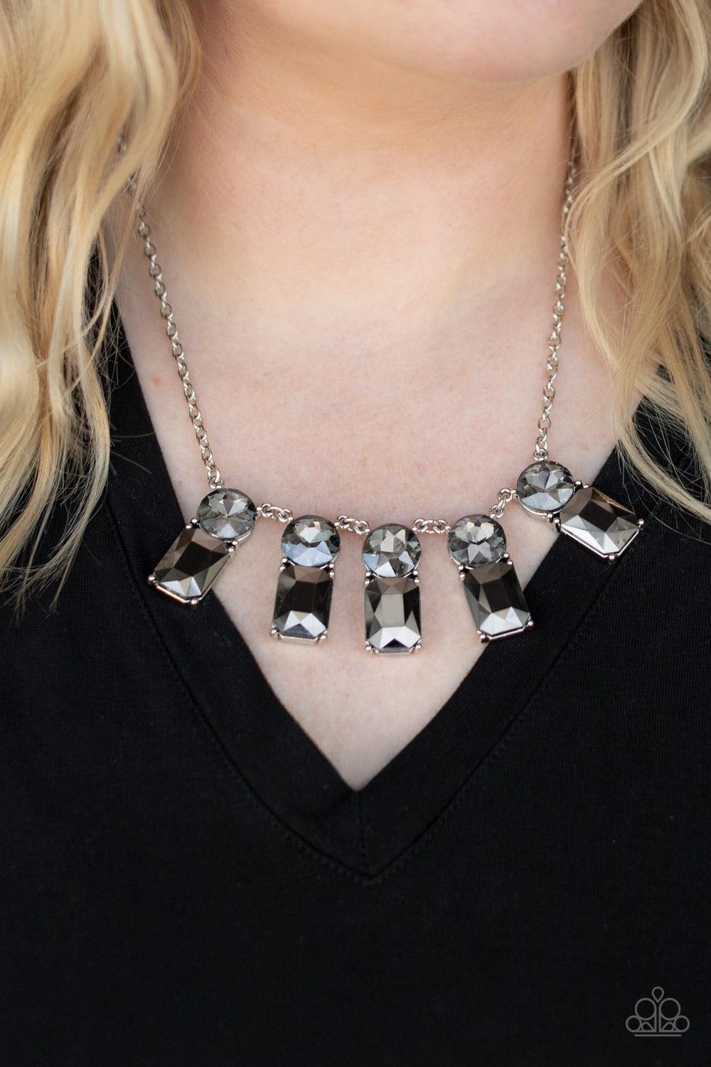 Paparazzi Accessories Celestial Royal - Silver Featuring classic pronged fittings, a dramatic collection of oversized smoky rhinestones and emerald cut hematite gems fan out below the collar for an outrageous sparkle. Features an adjustable clasp closure.
