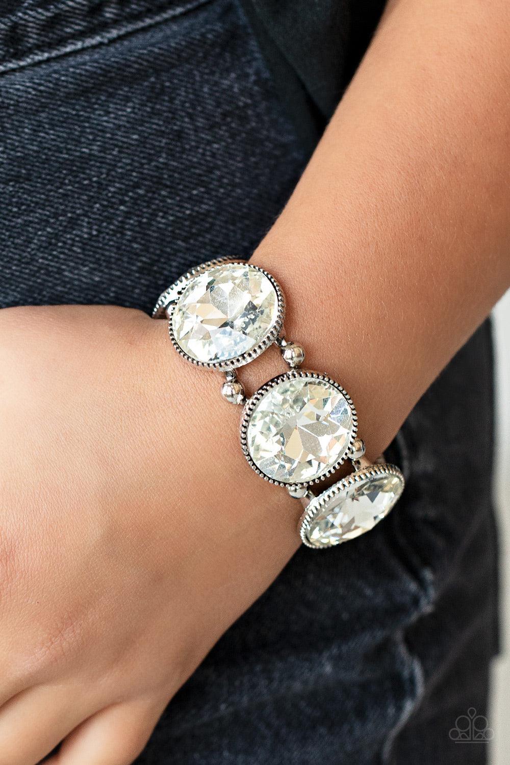Paparazzi Accessories Powerhouse Hustle - White Infused with pairs of silver beads, a glitzy collection of dramatically oversized white rhinestone frames are threaded along stretchy bands around the wrist for a jaw-dropping dazzle. Sold as one individual