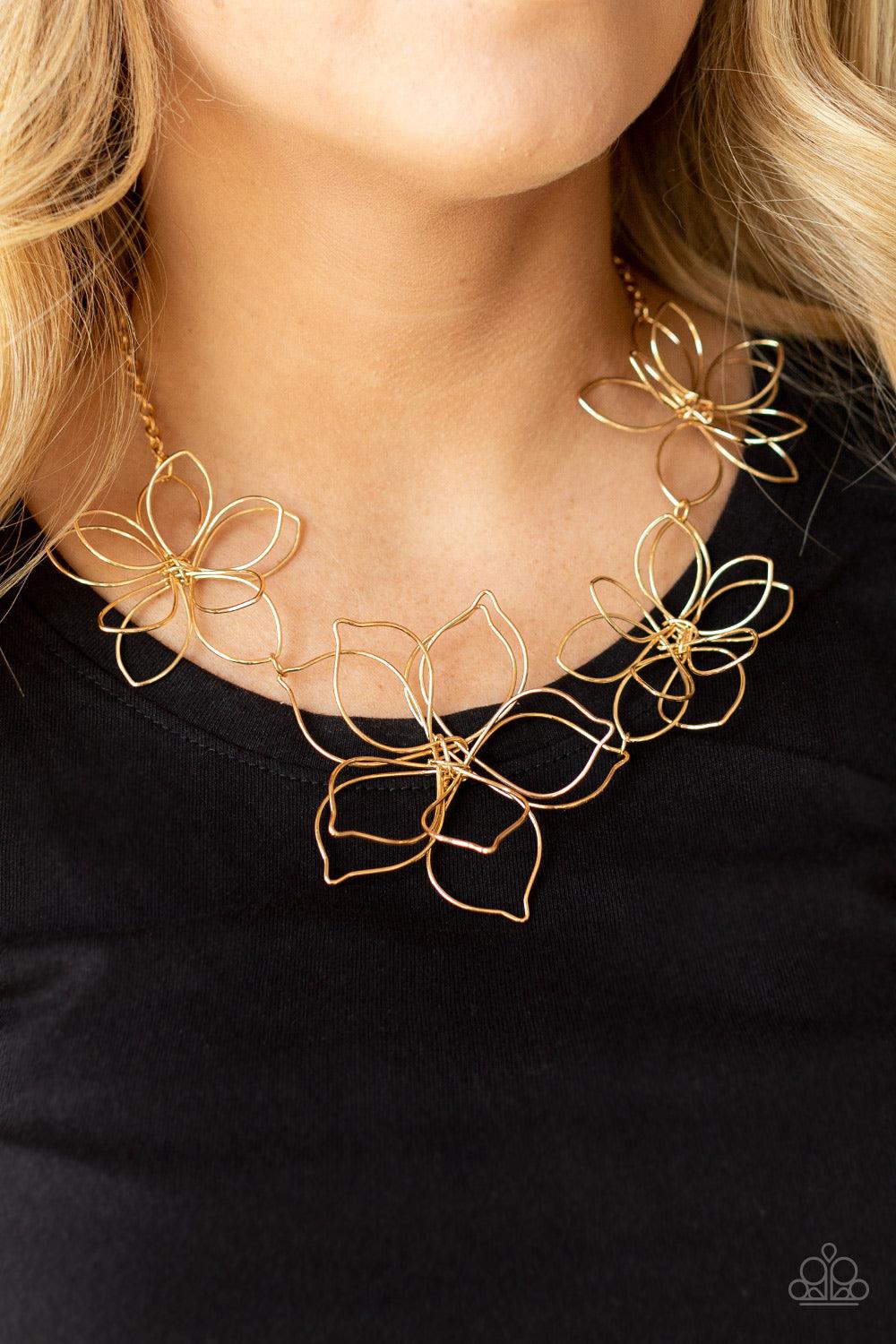 Paparazzi Accessories Flower Garden Fashionista - Gold Shiny gold wire delicately twists into oversized blossoms. Varying in size, the airy floral frames delicately link into an asymmetrical display as the layered frames elegantly pop beneath the collar.