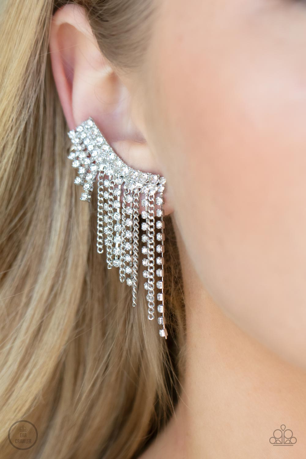 Paparazzi Accessories Thunderstruck Sparkle - White A tapered fringe of dainty silver chains and glittery strands of white rhinestones cascades from the edge of a curving white rhinestone encrusted frame, creating an edgy centerpiece. Features a clip-on f
