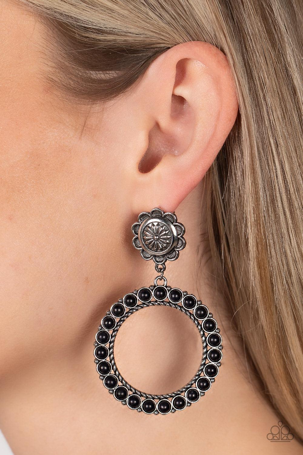 Paparazzi Accessories Playfully Prairie - Black Featuring studded and twisted rope-like silver accents, a black stone dotted hoop swings from the bottom of a rustic silver flower for a whimsically floral fashion. Earring attaches to a standard post fittin